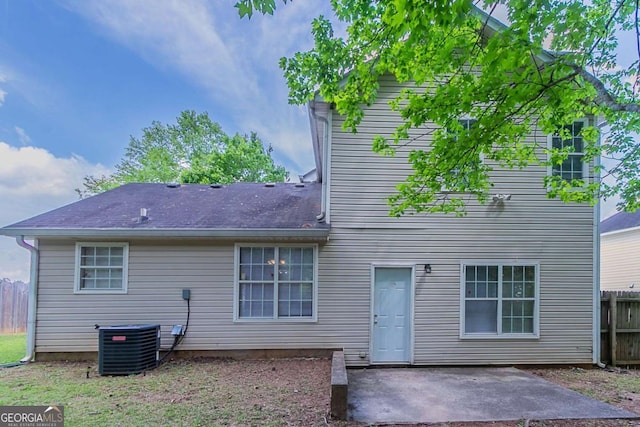 rear view of house featuring a patio, central AC unit, fence, and roof with shingles