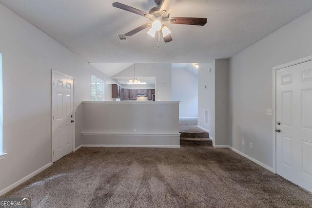 spare room with carpet floors, a chandelier, ceiling fan, vaulted ceiling, and baseboards