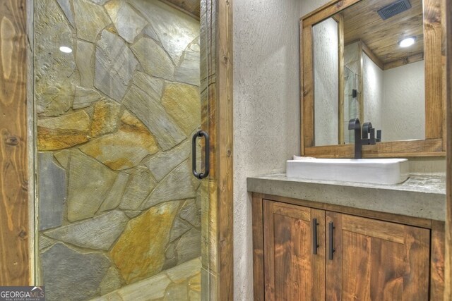 bathroom featuring vanity, a textured wall, and a stall shower