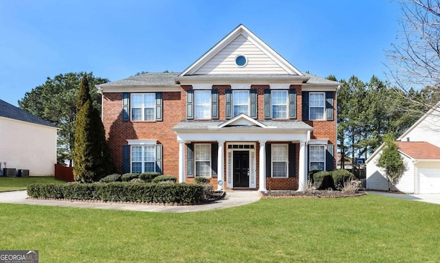 colonial inspired home featuring a garage, central AC unit, a front yard, and brick siding