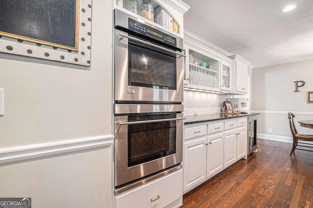 kitchen with stainless steel double oven, beverage cooler, a textured ceiling, white cabinetry, and dark wood-style floors