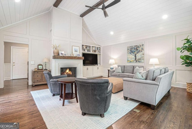 living area featuring ceiling fan, lofted ceiling with beams, and a decorative wall