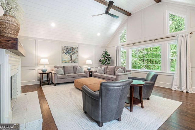living area featuring wood finished floors, a decorative wall, beam ceiling, high vaulted ceiling, and a ceiling fan
