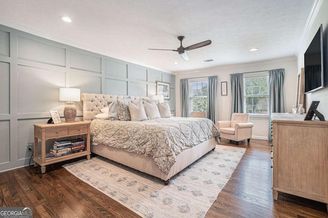bedroom with a decorative wall, dark wood finished floors, recessed lighting, visible vents, and ornamental molding