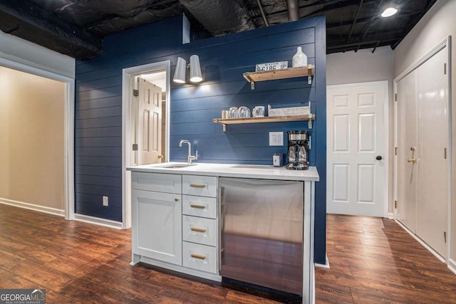 bar featuring a sink, wet bar, dark wood-style flooring, and fridge