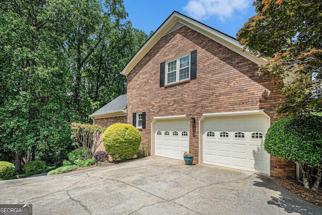 view of home's exterior featuring brick siding, a garage, and driveway