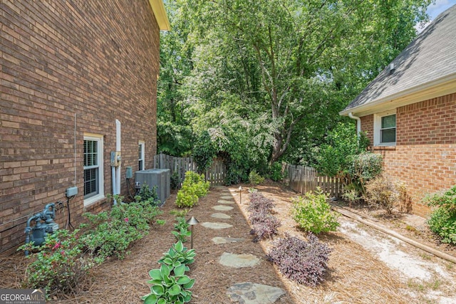 view of yard with central AC unit and fence
