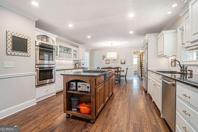 kitchen featuring open shelves, appliances with stainless steel finishes, a sink, a kitchen island, and ornamental molding
