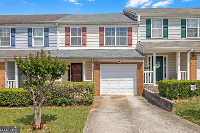 multi unit property with a porch, an attached garage, driveway, and brick siding
