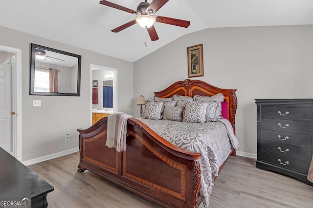 bedroom featuring lofted ceiling, baseboards, ensuite bathroom, light wood-type flooring, and a ceiling fan