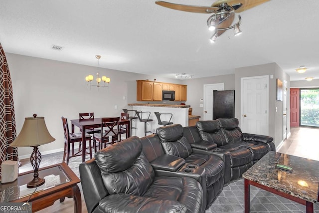 living area with baseboards, ceiling fan with notable chandelier, and visible vents