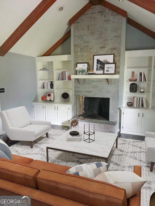 living area with wood finished floors, built in features, vaulted ceiling with beams, and a fireplace