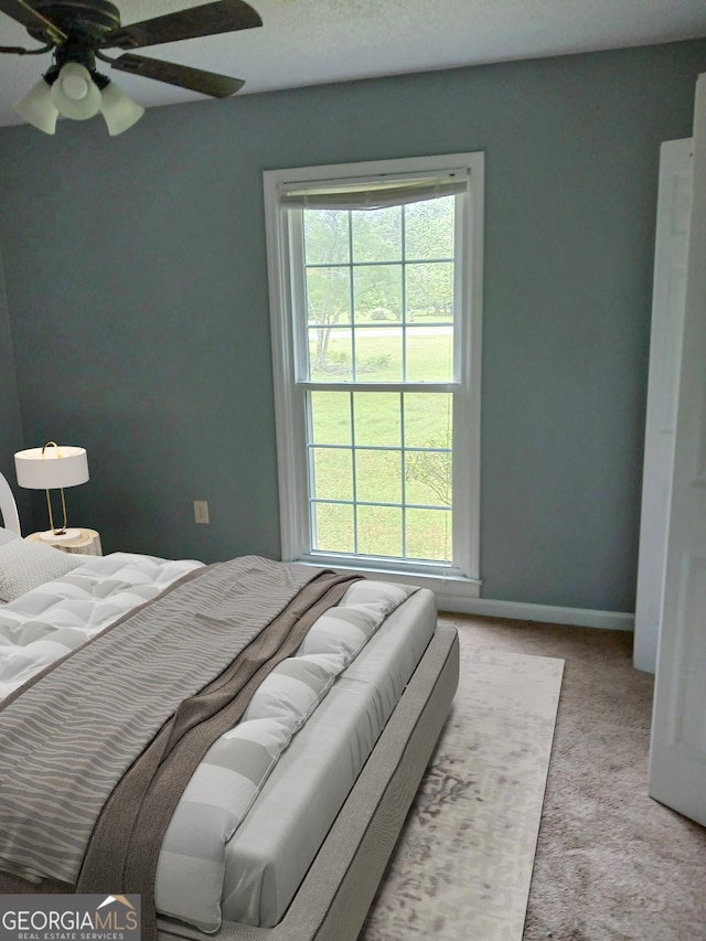 bedroom featuring carpet floors, a ceiling fan, baseboards, and multiple windows