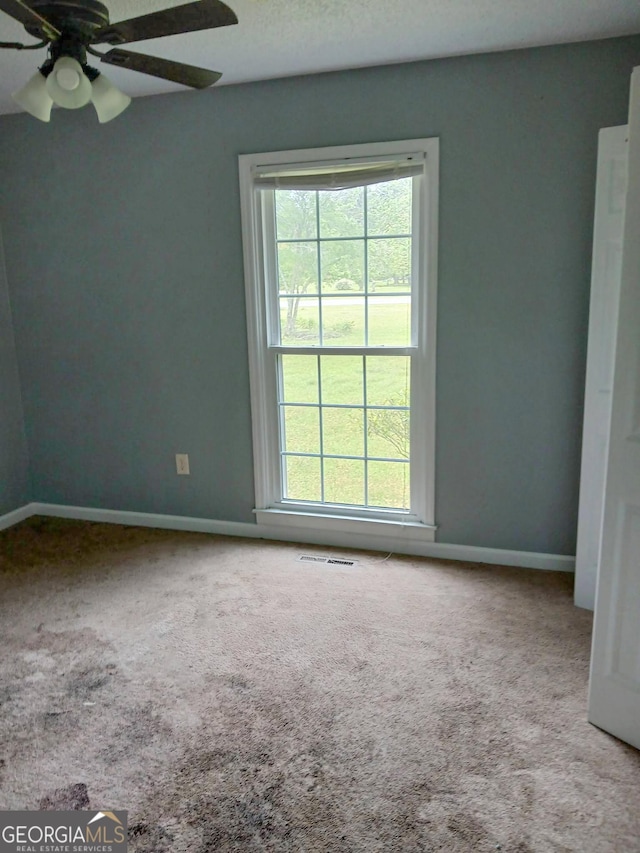 unfurnished room with ceiling fan, a healthy amount of sunlight, and carpet