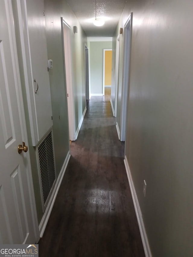 corridor with visible vents, baseboards, and wood finished floors