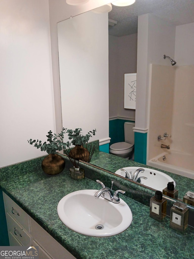 full bathroom featuring vanity, a textured ceiling, toilet, and shower / washtub combination