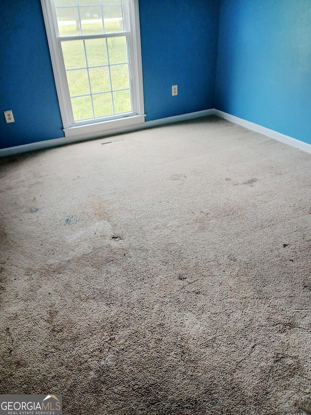 spare room featuring carpet floors and baseboards