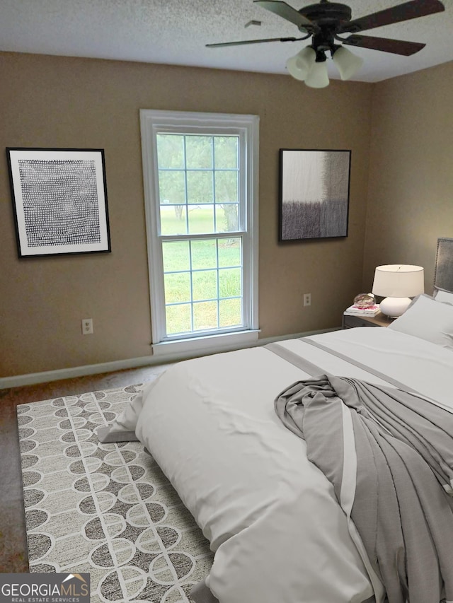 carpeted bedroom featuring baseboards, ceiling fan, and multiple windows