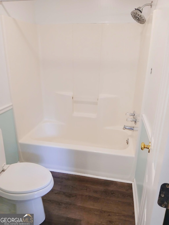 bathroom with shower / bathtub combination, toilet, and wood finished floors