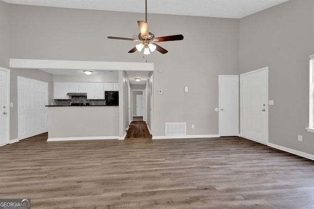 1774 Northwick Pl, Lithonia, GA 30058 - unfurnished living room with high vaulted ceiling, a ceiling fan, baseboards, wood finished floors, and visible vents