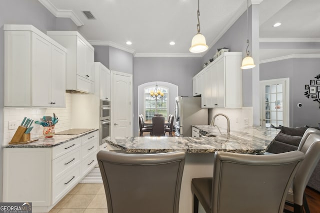 kitchen featuring visible vents, a peninsula, light stone countertops, tasteful backsplash, and appliances with stainless steel finishes