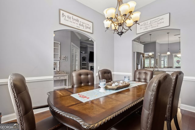 dining room featuring baseboards, arched walkways, a notable chandelier, and dark wood-style floors