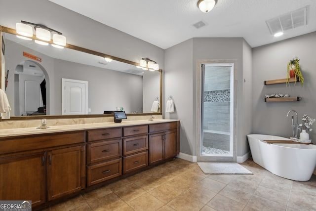 full bath with a sink, a shower stall, double vanity, and visible vents