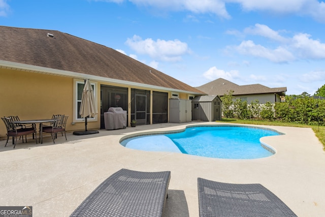 view of swimming pool with an outdoor structure, a storage unit, a sunroom, a fenced in pool, and a patio area