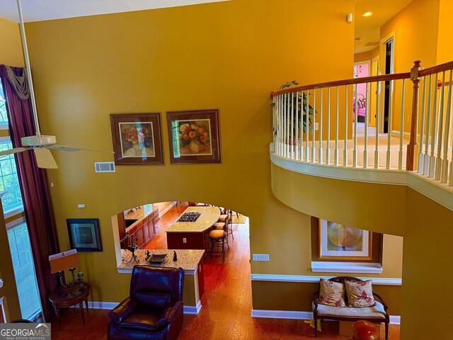 interior space featuring baseboards, visible vents, wood finished floors, and a high ceiling
