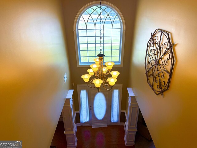 foyer featuring a decorative wall, an inviting chandelier, and a towering ceiling