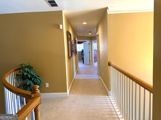 hallway with baseboards, visible vents, carpet, and an upstairs landing