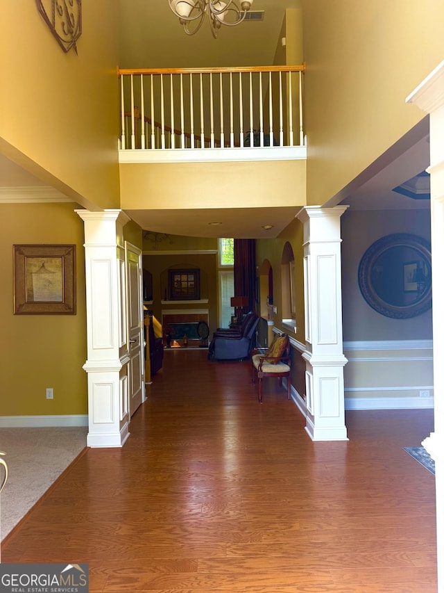 entrance foyer with arched walkways, a high ceiling, a fireplace, and ornate columns