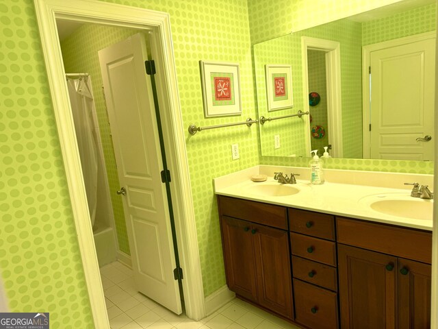 full bathroom featuring a sink, tile patterned floors, wallpapered walls, and double vanity