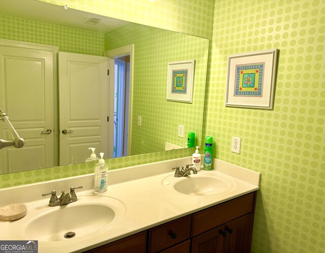 bathroom featuring a sink, wallpapered walls, and double vanity