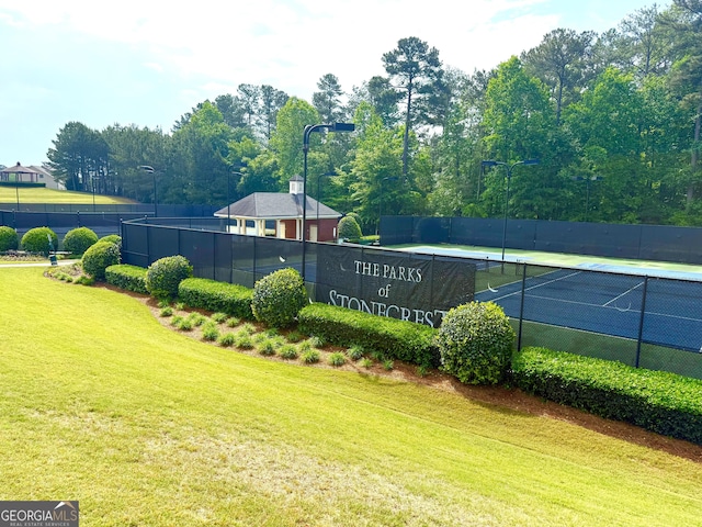 view of sport court with a lawn and fence