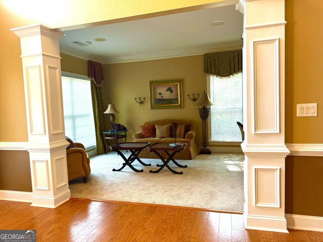 living room with ornate columns, ornamental molding, plenty of natural light, and wood finished floors