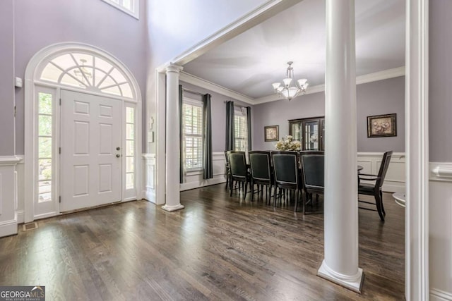 entryway featuring a healthy amount of sunlight, decorative columns, wood finished floors, and a notable chandelier