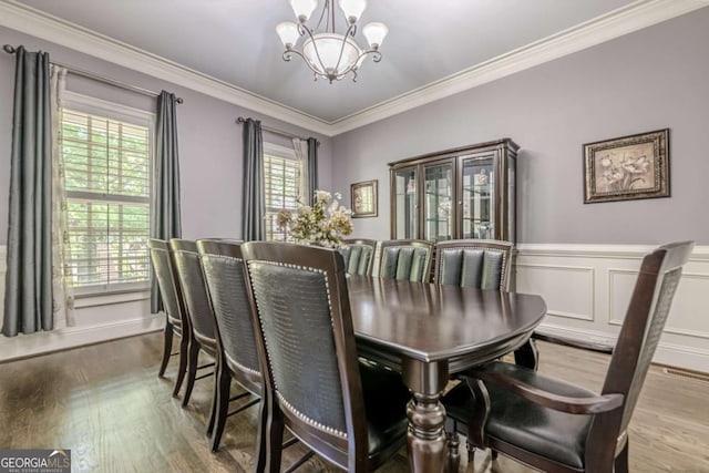 dining room with an inviting chandelier, ornamental molding, wood finished floors, and visible vents