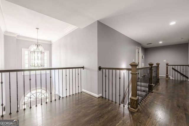 hall featuring an inviting chandelier, baseboards, wood finished floors, and an upstairs landing