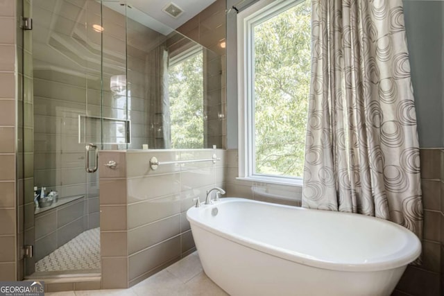 full bath featuring visible vents, a freestanding bath, tile walls, a stall shower, and tile patterned floors