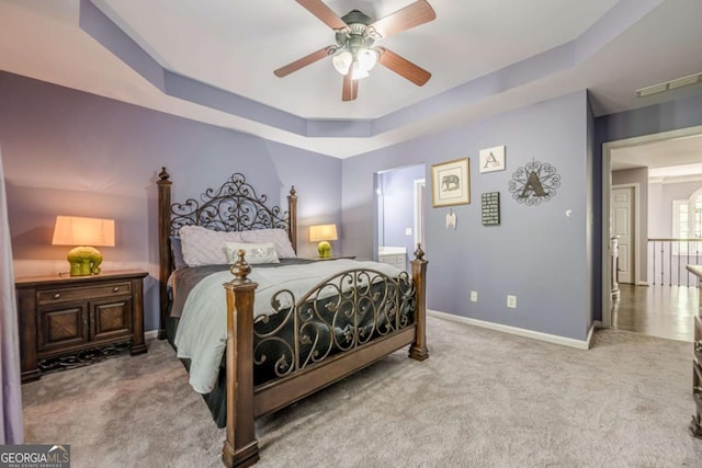 carpeted bedroom featuring a tray ceiling, ceiling fan, and baseboards