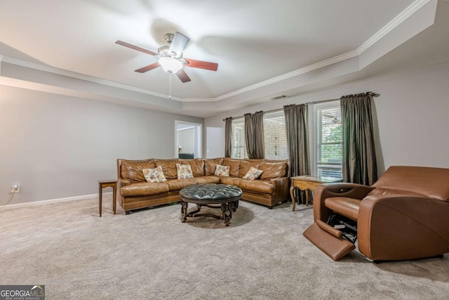 carpeted living area featuring visible vents, ornamental molding, baseboards, a tray ceiling, and a ceiling fan