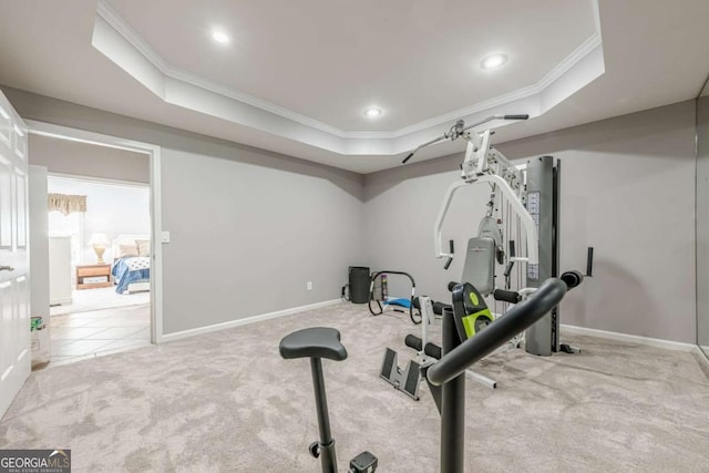 workout room featuring a tray ceiling, ornamental molding, and carpet
