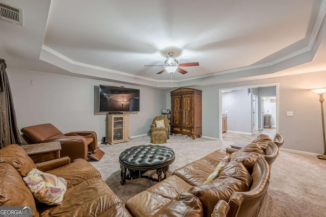 living area with light carpet, a ceiling fan, a tray ceiling, visible vents, and ornamental molding
