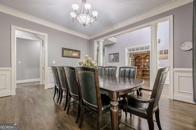 dining room featuring dark wood-style flooring, a chandelier, wainscoting, and ornate columns