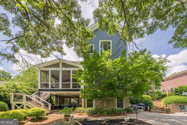 back of property with a sunroom and stairway