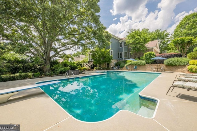 outdoor pool featuring a diving board and a patio area