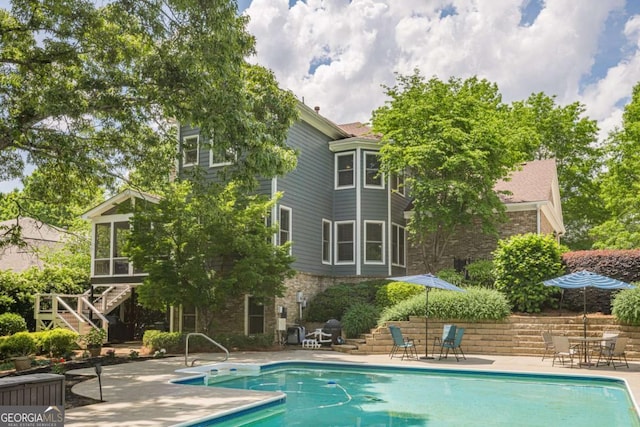 pool featuring stairs, a sunroom, and a patio area