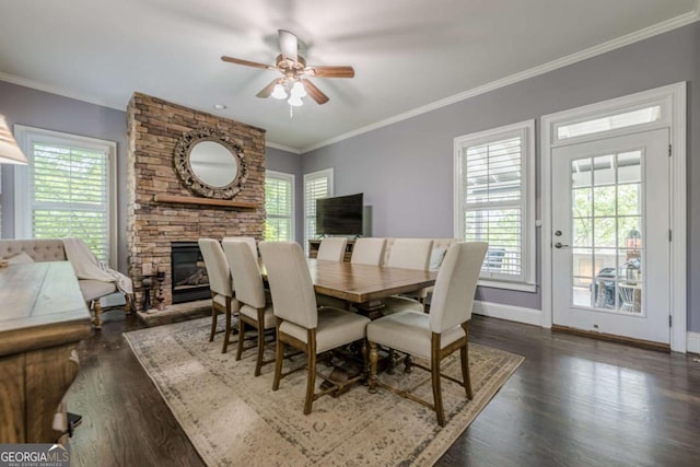 dining space with ornamental molding, a fireplace, baseboards, ceiling fan, and dark wood-style floors
