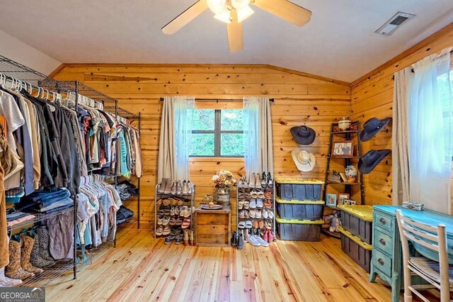 interior space with ceiling fan, vaulted ceiling, visible vents, and hardwood / wood-style floors